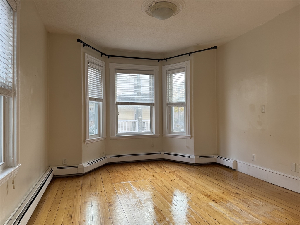 9 Kenney Street, Unit 1 Boston, MA 02130 - Photo 1 of 12 an empty room with wooden floor and windows