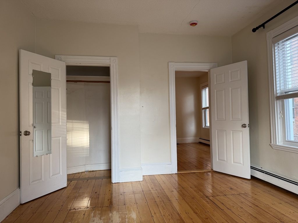 9 Kenney Street, Unit 1 Boston, MA 02130 - Photo 2 of 12 an empty room with wooden floor and windows