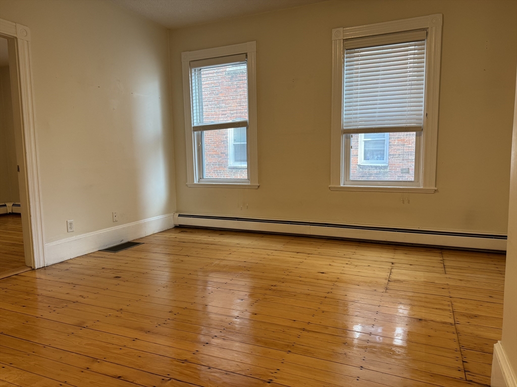 9 Kenney Street, Unit 1 Boston, MA 02130 - Photo 3 of 12 a view of an empty room with wooden floor and a window