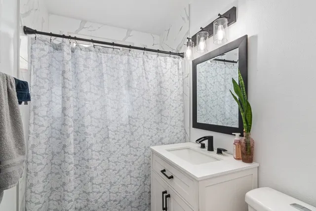 a bathroom with a sink vanity mirror and toilet