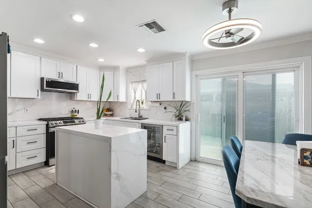 a kitchen with stainless steel appliances granite countertop a sink a stove a refrigerator cabinets and a dining table