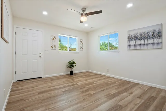 an empty room with windows and ceiling fan