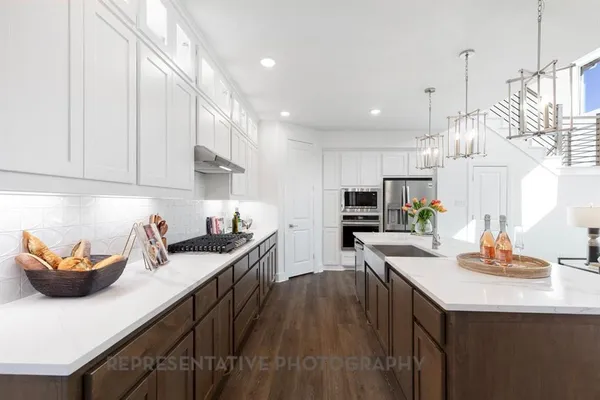 a kitchen with stainless steel appliances granite countertop a sink a stove and a wooden floors