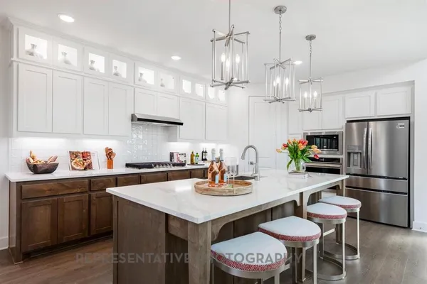 a kitchen with a refrigerator a stove a kitchen island and chairs with wooden floor