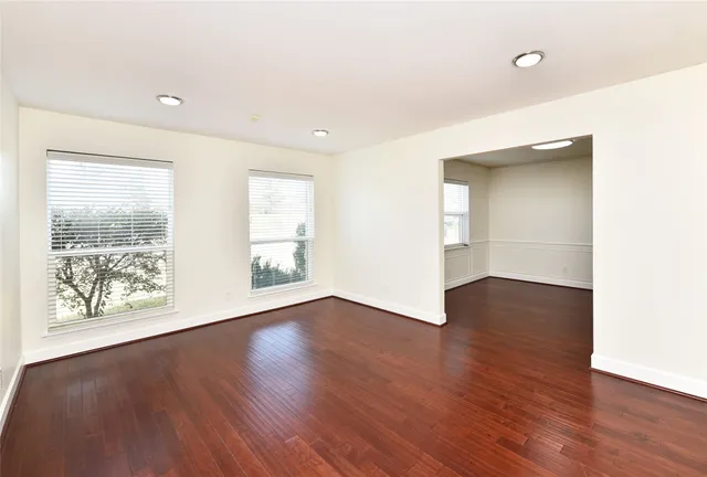 a view of an empty room with wooden floor and a window