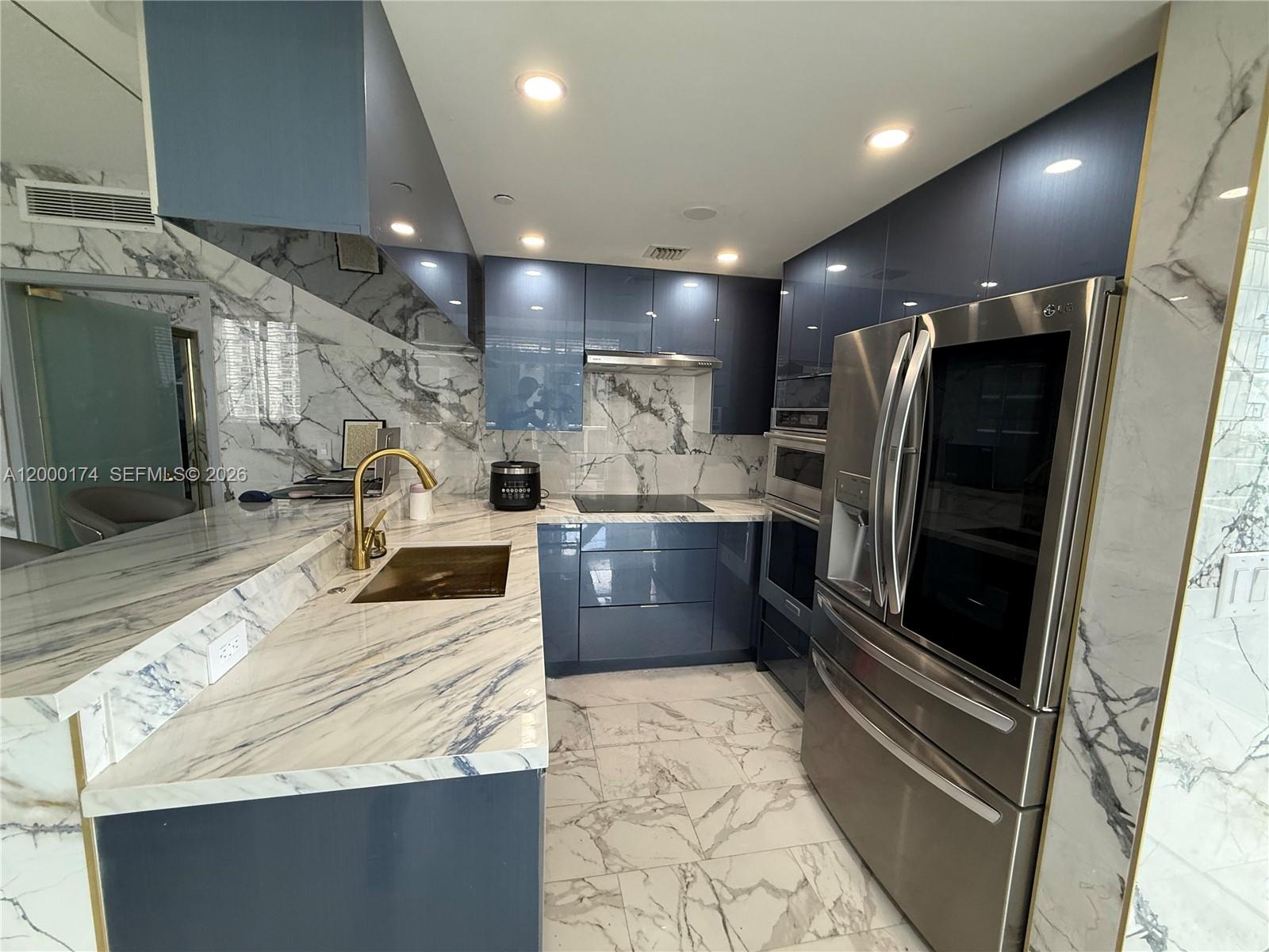 a kitchen with stainless steel appliances kitchen island granite countertop a refrigerator and a sink