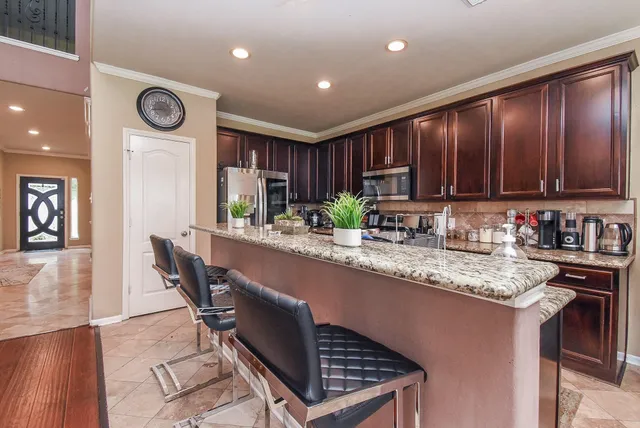 a kitchen with granite countertop a stove a sink a dining table and chairs