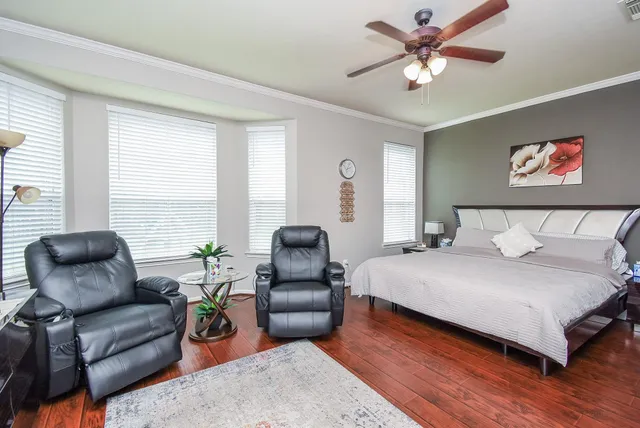 a bedroom with a bed couch and windows