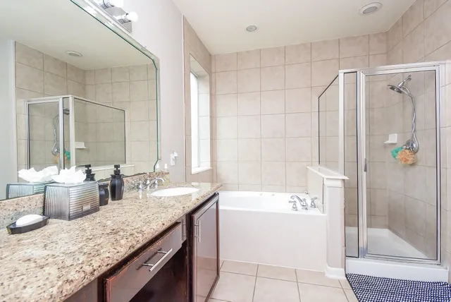 a bathroom with a granite countertop sink a mirror a bathtub and next to a window