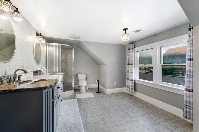 a spacious bathroom with a double vanity sink a mirror and next to a window