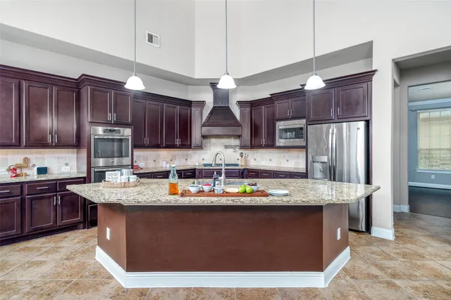 a kitchen with stainless steel appliances granite countertop a sink a stove a refrigerator cabinets and wooden floor
