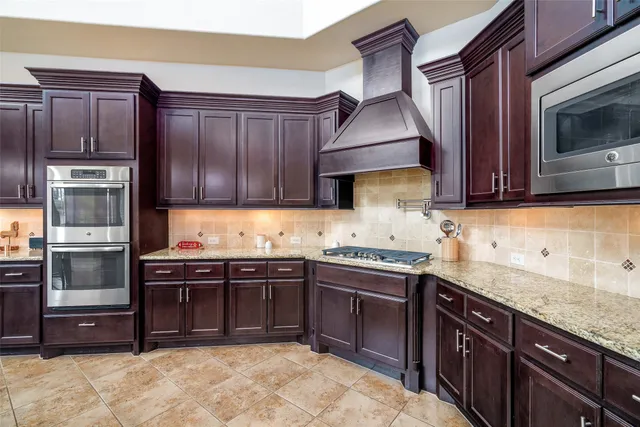 a kitchen with stainless steel appliances granite countertop wooden cabinets and a stove top oven