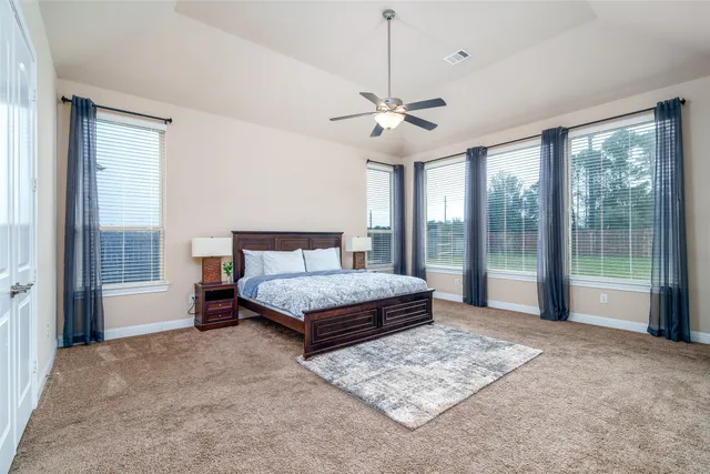 a bedroom with a large bed and a chandelier fan
