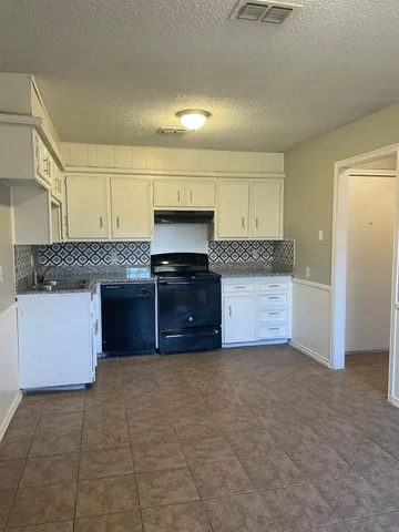 a large kitchen with granite countertop a stove a sink and a microwave