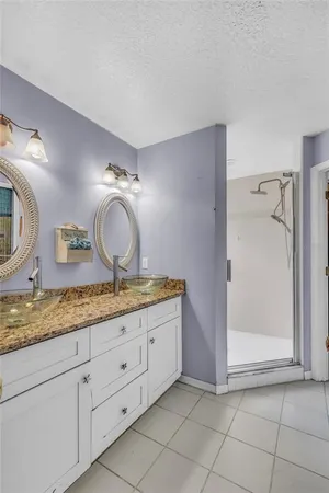 a bathroom with a granite countertop sink a mirror and shower