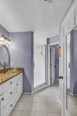 a spacious bathroom with a granite countertop sink a mirror and shower