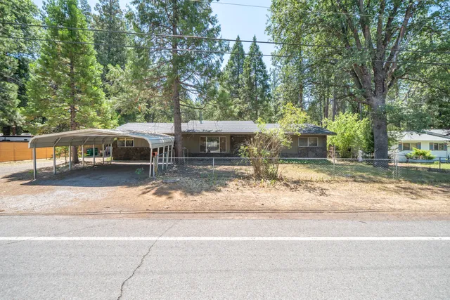 a view of a house with a yard and large tree
