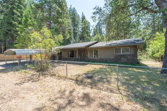 a backyard of a house with table and chairs under an umbrella