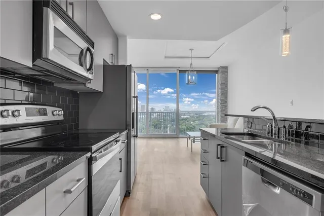 a kitchen with stainless steel appliances granite countertop a sink a stove and a wooden cabinets
