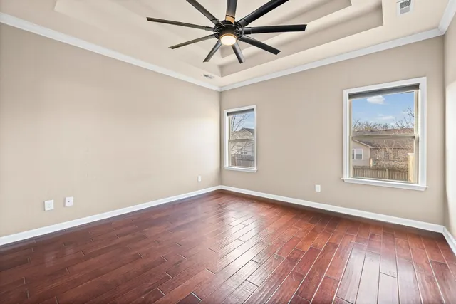 a view of an empty room with window and wooden floor