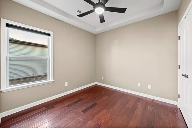 a view of an empty room with wooden floor and a window