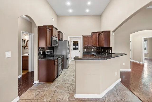 a kitchen with stainless steel appliances granite countertop a refrigerator a stove a sink a washer and dryer