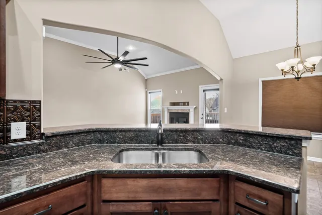 a kitchen with kitchen island granite countertop a sink a counter cabinets and stainless steel appliances