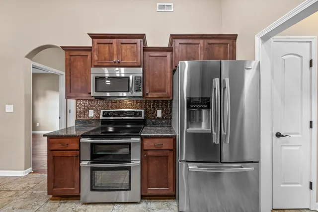 a kitchen with stainless steel appliances granite countertop a refrigerator and a stove top oven