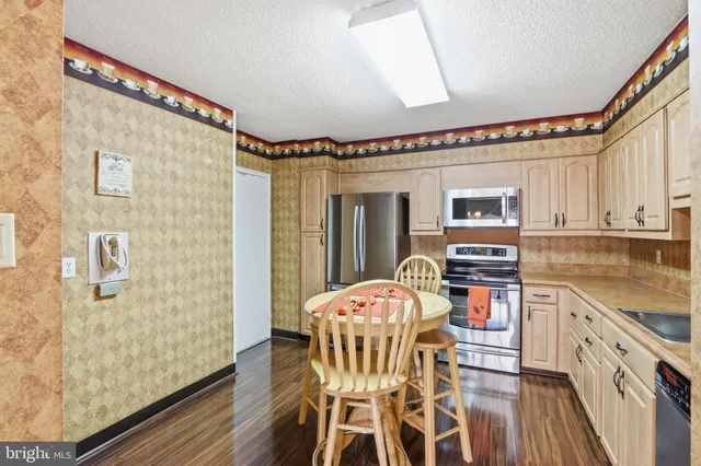a kitchen with stainless steel appliances kitchen island granite countertop a table chairs in it and wooden floors