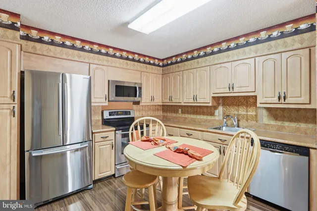 a kitchen with stainless steel appliances granite countertop a refrigerator a sink a stove a dining table and chairs