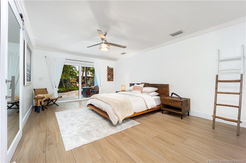 3713 Southeast Matanzas Street Stuart, FL 34996 - Photo 34 of 53 a spacious bedroom with a bed a table and a large window