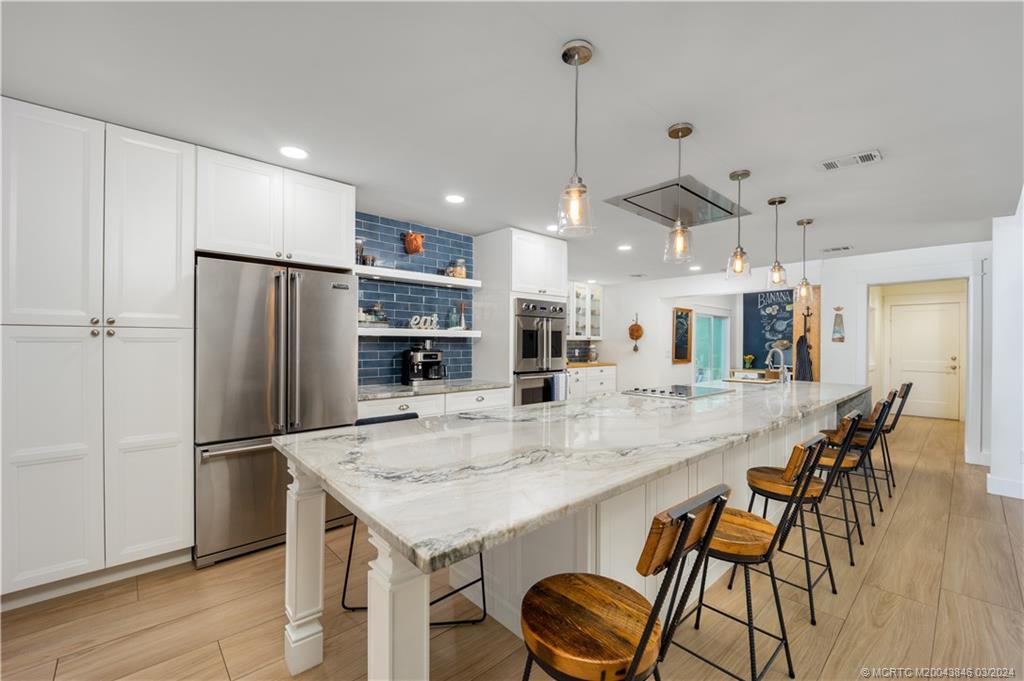 3713 Southeast Matanzas Street Stuart, FL 34996 - Photo 5 of 53 a kitchen with stainless steel appliances granite countertop a kitchen island a stove a table and chairs
