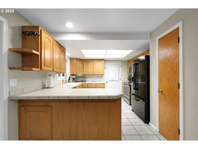a kitchen with kitchen island granite countertop stainless steel appliances a sink refrigerator and cabinets