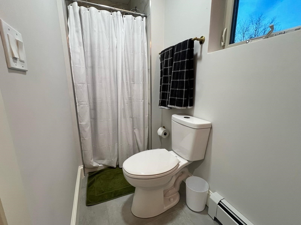 81 Stuart Street Gardner, MA 01440 - Photo 19 of 24 a white toilet sitting next to a shower curtain