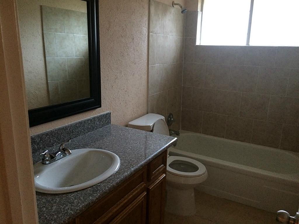 16826 Rippling Mill Drive Sugar Land, TX 77498 - Photo 4 of 18 a bathroom with a granite countertop sink toilet and a mirror