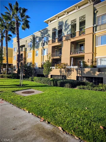 a front view of a building with garden and trees
