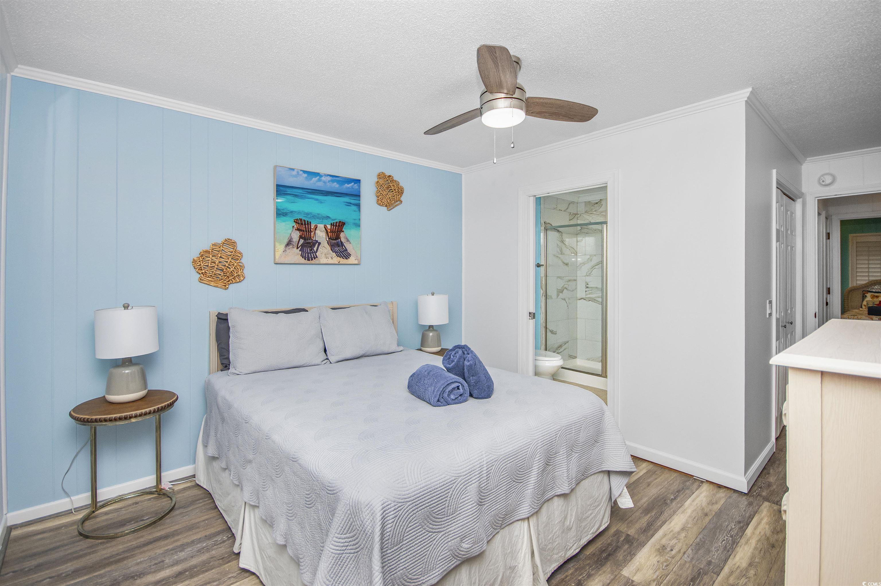 9530 Shore Drive, Unit 2D Myrtle Beach, SC 29572 - Photo 16 of 25 Bedroom featuring crown molding, a textured ceiling, dark wood finished floors, a ceiling fan, and connected bathroom