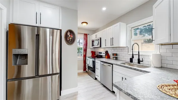 a kitchen with stainless steel appliances granite countertop a refrigerator sink and white cabinets