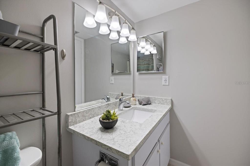 1604 Stickney Point Road, Unit 4102 Sarasota, FL 34231 - Photo 14 of 30 a bathroom with a granite countertop sink a toilet and mirror