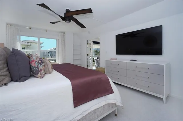 a bedroom with a bed a flat screen tv and a chandelier