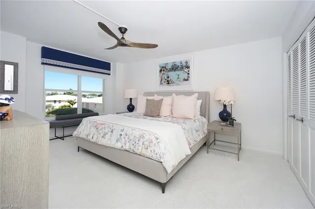 a bedroom with a bed painting on wall and a large window