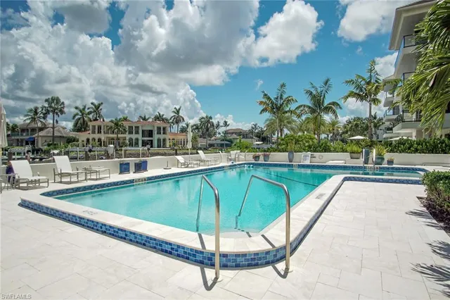 a view of a swimming pool with a bench and trees in the background