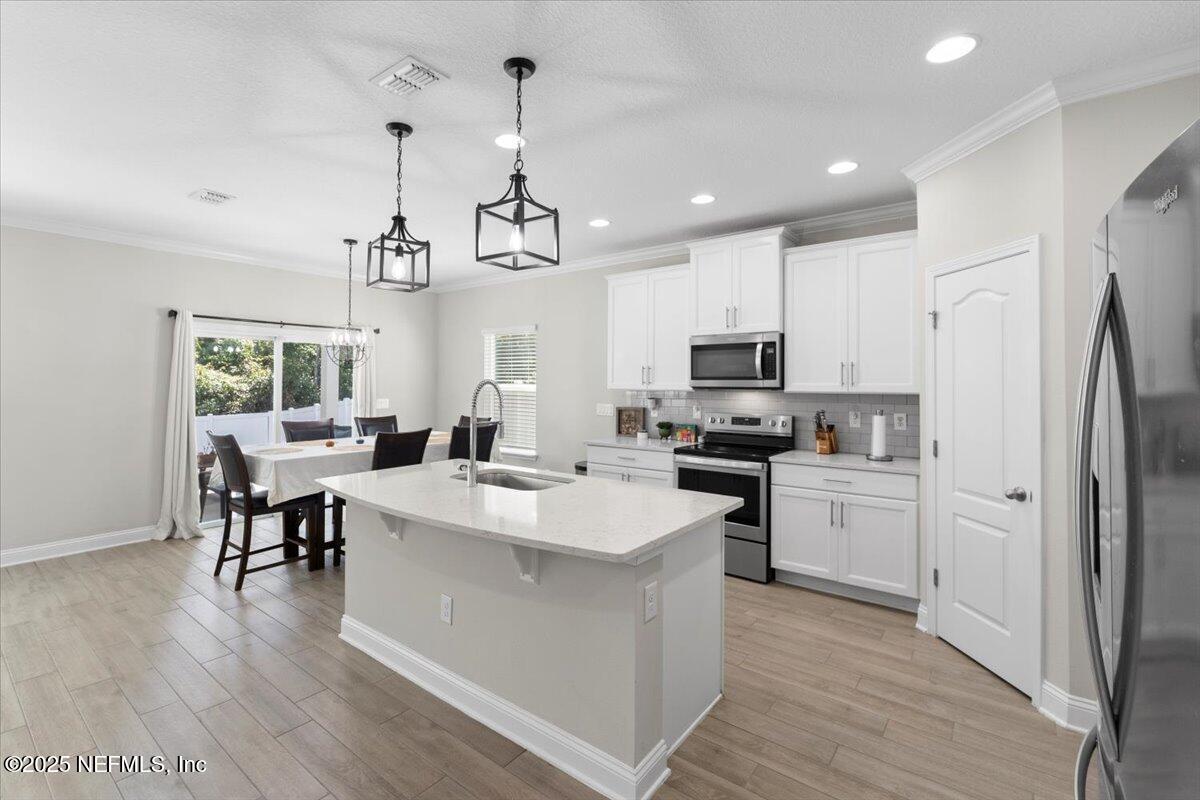 3060 Free Bird Loop Green Cove Springs, FL 32043 - Photo 7 of 94 a kitchen with stainless steel appliances granite countertop a refrigerator a stove top oven a sink dishwasher a dining table and chairs with wooden floor