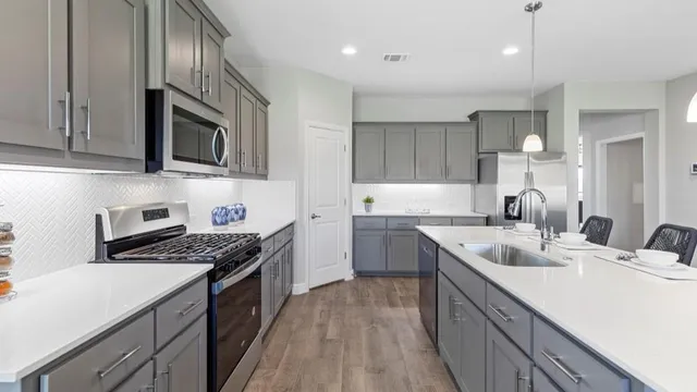 a kitchen with stainless steel appliances granite countertop a stove a refrigerator a sink a microwave and chairs