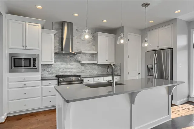 a kitchen with stainless steel appliances granite countertop a sink a stove and a refrigerator