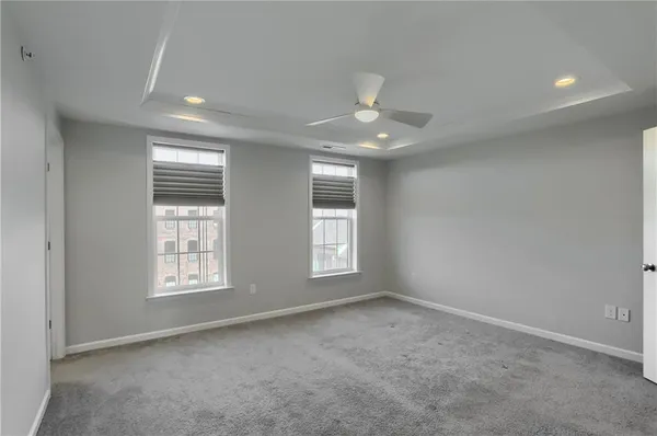 an empty room with windows and ceiling fan
