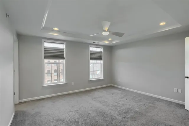 an empty room with windows and ceiling fan