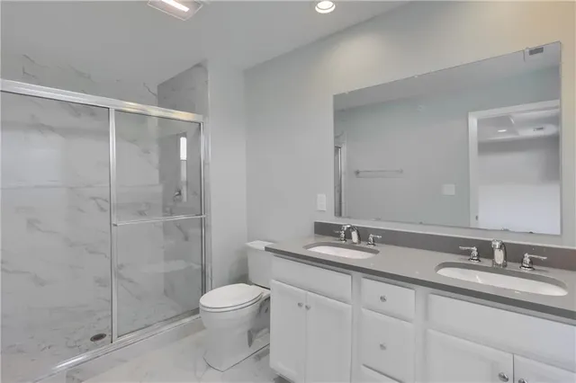 a bathroom with a granite countertop sink a toilet and shower