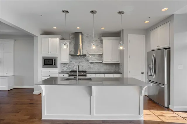 a large kitchen with stainless steel appliances granite countertop a refrigerator a oven a sink and a white cabinets