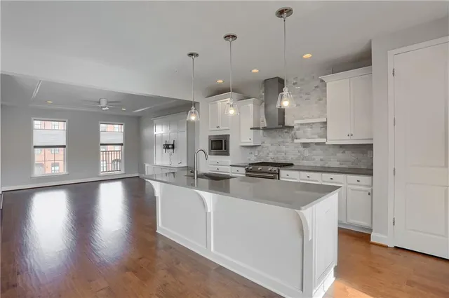 a large kitchen with kitchen island a stove a sink a refrigerator and a fireplace with wooden floor